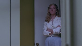 Movie still from “Gia” (1998), directed by Michael Cristofer – A woman standing in front of a door with her arms crossed; Medium shot, Low angle
