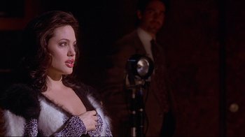 Movie still from “Gia” (1998), directed by Michael Cristofer – A woman standing next to a man in a suit; Close Up shot, Over the shoulder angle