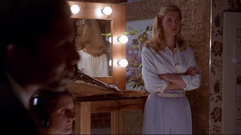 Movie still from “Gia” (1998), directed by Michael Cristofer – A woman standing in front of a mirror in a dressing room; Medium shot, Over the shoulder angle