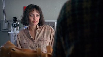 Movie still from “Gia” (1998), directed by Michael Cristofer – A woman looking into a mirror while wearing a brown shirt; Close Up shot, Over the shoulder angle