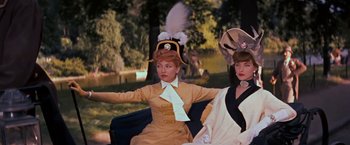 Movie still from “Gigi” (1958), directed by Vincente Minnelli – Two women sitting on a park bench wearing fancy hats; Medium shot, Low angle