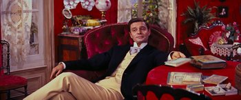 Movie still from “Gigi” (1958), directed by Vincente Minnelli – A man sitting in a chair wearing a suit and bow tie; Medium shot, Low angle
