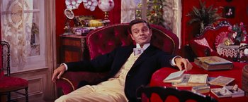 Movie still from “Gigi” (1958), directed by Vincente Minnelli – A man sitting in a chair wearing a suit and bow tie; Medium shot, High angle