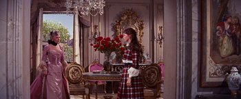 Movie still from “Gigi” (1958), directed by Vincente Minnelli – A woman standing in front of a dining room table; Wide shot, Over the shoulder angle