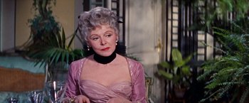 Movie still from “Gigi” (1958), directed by Vincente Minnelli – An older woman in a pink dress sitting in a chair; Close Up shot, Over the shoulder angle