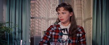 Movie still from “Gigi” (1958), directed by Vincente Minnelli – A woman sitting at a table with a glass of water; Close Up shot, Over the shoulder angle