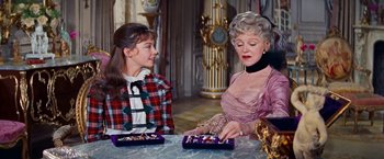 Movie still from “Gigi” (1958), directed by Vincente Minnelli – Two women sitting at a table with a box of chocolates; Medium shot, Over the shoulder angle