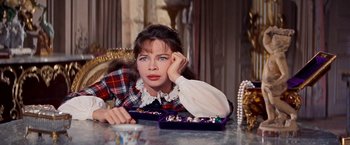 Movie still from “Gigi” (1958), directed by Vincente Minnelli – A woman sitting at a table in front of a tray of candy; Close Up shot, Over the shoulder angle