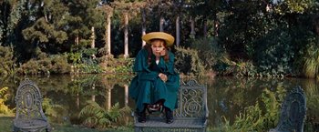 Movie still from “Gigi” (1958), directed by Vincente Minnelli – A woman sitting on top of a park bench wearing a hat; Medium shot, High angle