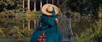 Movie still from “Gigi” (1958), directed by Vincente Minnelli – A woman sitting on top of a bench wearing a hat; Medium shot, High angle