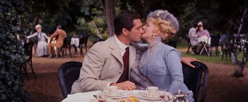 Movie still from “Gigi” (1958), directed by Vincente Minnelli – A man and a woman kissing at a dinner table; Medium shot, Over the shoulder angle