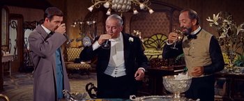 Movie still from “Gigi” (1958), directed by Vincente Minnelli – An older man in a tuxedo drinking a glass of wine; Medium shot, Low angle