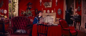 Movie still from “Gigi” (1958), directed by Vincente Minnelli – A woman sitting at a table reading a book; Wide shot, High angle