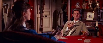 Movie still from “Gigi” (1958), directed by Vincente Minnelli – A man sitting at a table holding a deck of playing cards; Medium shot, Over the shoulder angle