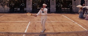 Movie still from “Gigi” (1958), directed by Vincente Minnelli – A man in a white suit holding a tennis racquet on a tennis court; Medium shot, High angle