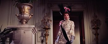 Movie still from “Gigi” (1958), directed by Vincente Minnelli – A woman in a fancy costume standing in front of a door; Medium shot, Low angle