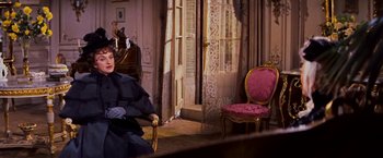 Movie still from “Gigi” (1958), directed by Vincente Minnelli – A woman sitting on a chair in a room; Medium shot, Over the shoulder angle