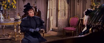 Movie still from “Gigi” (1958), directed by Vincente Minnelli – A woman sitting on a chair in a room; Medium shot, Over the shoulder angle