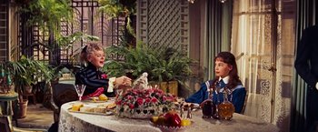 Movie still from “Gigi” (1958), directed by Vincente Minnelli – Two people are sitting at a table with food and drinks; Medium shot, High angle