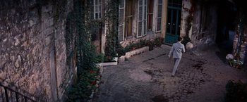 Movie still from “Gigi” (1958), directed by Vincente Minnelli – A person walking down a street near a building; Wide shot, High angle