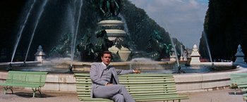 Movie still from “Gigi” (1958), directed by Vincente Minnelli – A man sitting on top of a green park bench; Wide shot, Low angle