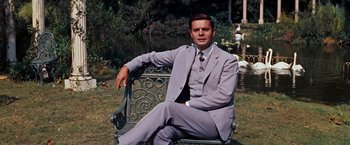 Movie still from “Gigi” (1958), directed by Vincente Minnelli – A man in a suit sitting on top of a metal bench; Medium shot, Low angle