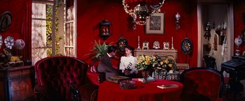 Movie still from “Gigi” (1958), directed by Vincente Minnelli – A man and a woman sitting at a table in front of a fireplace; Wide shot, High angle