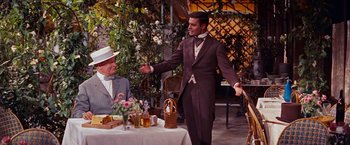 Movie still from “Gigi” (1958), directed by Vincente Minnelli – A man standing in front of a table holding a knife; Medium shot, Over the shoulder angle