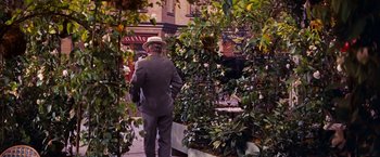 Movie still from “Gigi” (1958), directed by Vincente Minnelli – An older man wearing a straw hat walking through a garden; Wide shot, Over the shoulder angle
