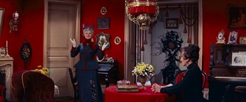 Movie still from “Gigi” (1958), directed by Vincente Minnelli – An older woman in a victorian dress and a man sitting at a table; Medium shot, Low angle