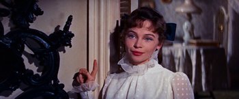 Movie still from “Gigi” (1958), directed by Vincente Minnelli – A woman in a white dress is giving the " y " sign; Close Up shot, Over the shoulder angle