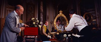 Movie still from “Gigi” (1958), directed by Vincente Minnelli – A man standing in front of a mirror in a room; Medium shot, Over the shoulder angle
