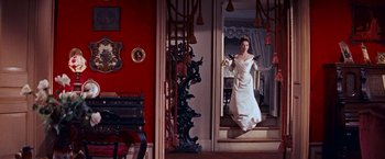 Movie still from “Gigi” (1958), directed by Vincente Minnelli – A woman in a white dress standing in front of a mirror; Wide shot, Low angle