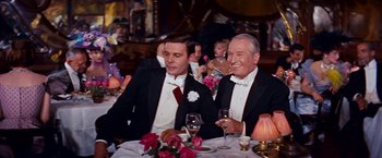 Movie still from “Gigi” (1958), directed by Vincente Minnelli – Two men in tuxedos sitting at a dinner table; Medium shot, Over the shoulder angle