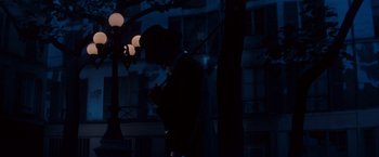 Movie still from “Gigi” (1958), directed by Vincente Minnelli – A man standing in the dark looking at his cell phone; Wide shot, Low angle