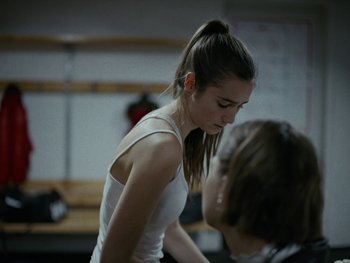 Movie still from “Girl Picture” (2022), directed by Alli Haapasalo – A young woman standing in front of another woman; Close Up shot, Over the shoulder angle