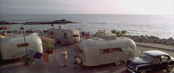 Movie still from “Gods and Monsters” (1998), directed by Bill Condon – A man standing in front of a couple of trailers on the side of the road; Extreme Wide shot, High angle