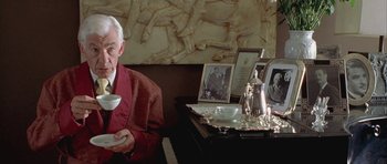 Movie still from “Gods and Monsters” (1998), directed by Bill Condon – An older man sitting at a table with a cup of coffee; Medium shot, Over the shoulder angle