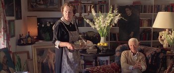 Movie still from “Gods and Monsters” (1998), directed by Bill Condon – An older woman holding a plate in a living room; Medium shot, High angle