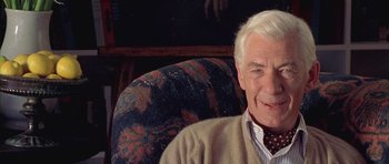 Movie still from “Gods and Monsters” (1998), directed by Bill Condon – An older man sitting in a chair smiling for the camera; Close Up shot, Low angle