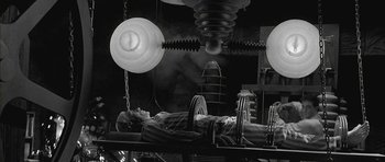 Movie still from “Gods and Monsters” (1998), directed by Bill Condon – A man laying on a bed in a room with lights; Wide shot, Low angle