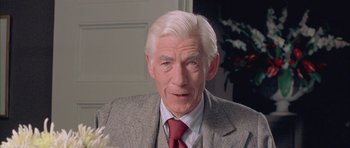 An older man wearing a suit and a red neck tie
