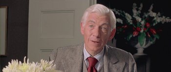An older man wearing a suit and a red neck tie