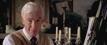 Movie still from “Gods and Monsters” (1998), directed by Bill Condon – An older man in a vest and a tie with candles in the background; Close Up shot, Over the shoulder angle