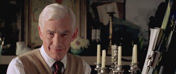 Movie still from “Gods and Monsters” (1998), directed by Bill Condon – An older man in a vest and a tie in front of candles; Close Up shot, Over the shoulder angle