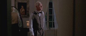 Movie still from “Gods and Monsters” (1998), directed by Bill Condon – An older man in a suit and bow tie standing in front of a window; Medium shot, Low angle