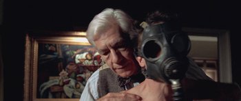 Movie still from “Gods and Monsters” (1998), directed by Bill Condon – An older man wearing a gas mask with a gas mask on his face; Close Up shot, Low angle