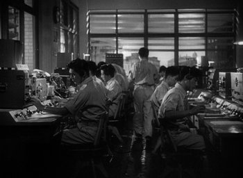 Movie still from “Godzilla” (1954), directed by Ishirô Honda – A black and white photo of people working in a factory; Wide shot, High angle