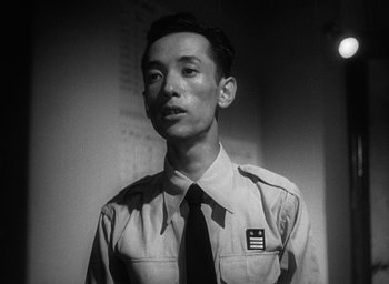 Movie still from “Godzilla” (1954), directed by Ishirô Honda – A man in a uniform is standing in a room; Close Up shot, Low angle