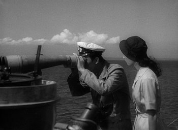 Movie still from “Godzilla” (1954), directed by Ishirô Honda – A man and a woman looking through a telescope; Medium shot, Low angle